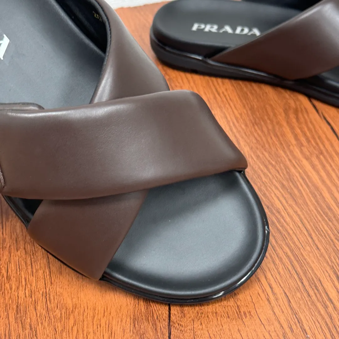 Batch 580 Prada/Prada's new men's leather cross slippers. Velcro closure can finely adjust the size. Calf leather light luxury slippers. Thick soft calf leather wraps the upper. Fat but soft rubber lazy style, soft and comfortable, excellent foot feel. Genuine leather bottom layer, cross style, with a Velcro closure buckle, easy to adjust the appropriate size, and a perfect fit for the wearing experience. The enamel gold triangle logo highlights the brand's classic features. Lightweight rubber thin sole, high foot comfort! Complete package! Size: 39-40-41-42-43-44-45 Leather shoe size Item number: 2X7132 Brown
